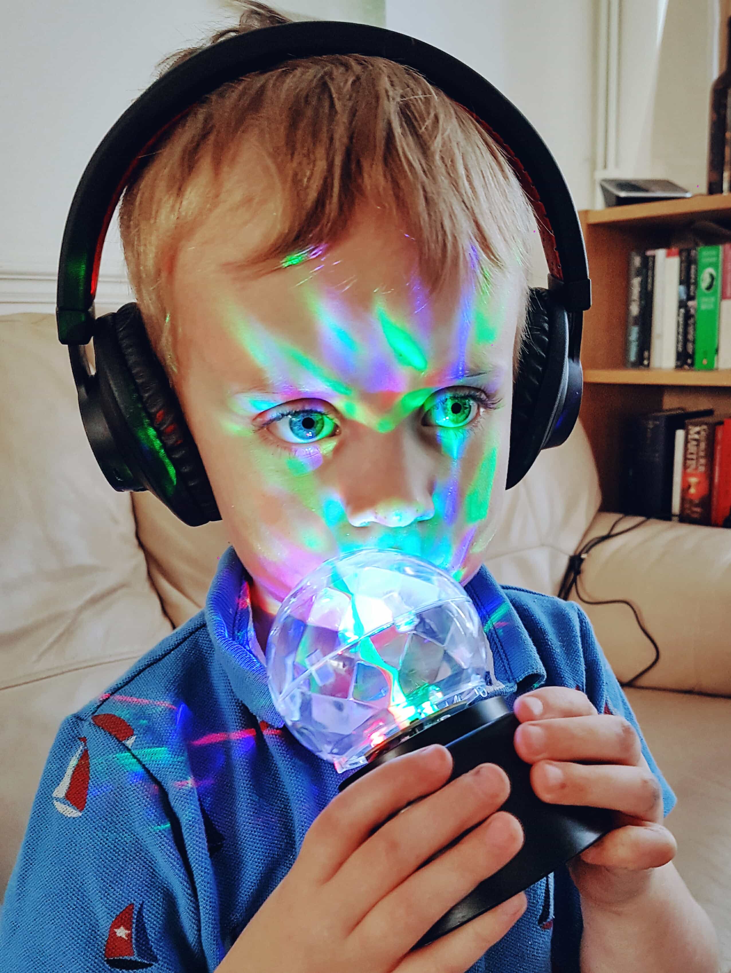 Boy with Bluetooth headphones and sensory toys which make good gifts for autistic children. Photo by Someone's Mum.