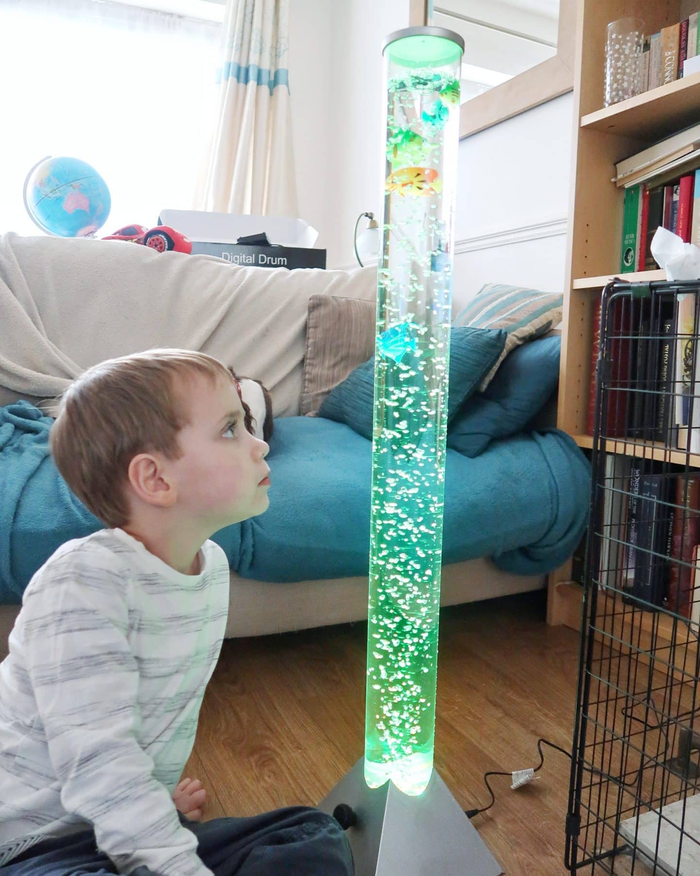 Boy staring at large bubble tube with a green light - gifts for autistic children