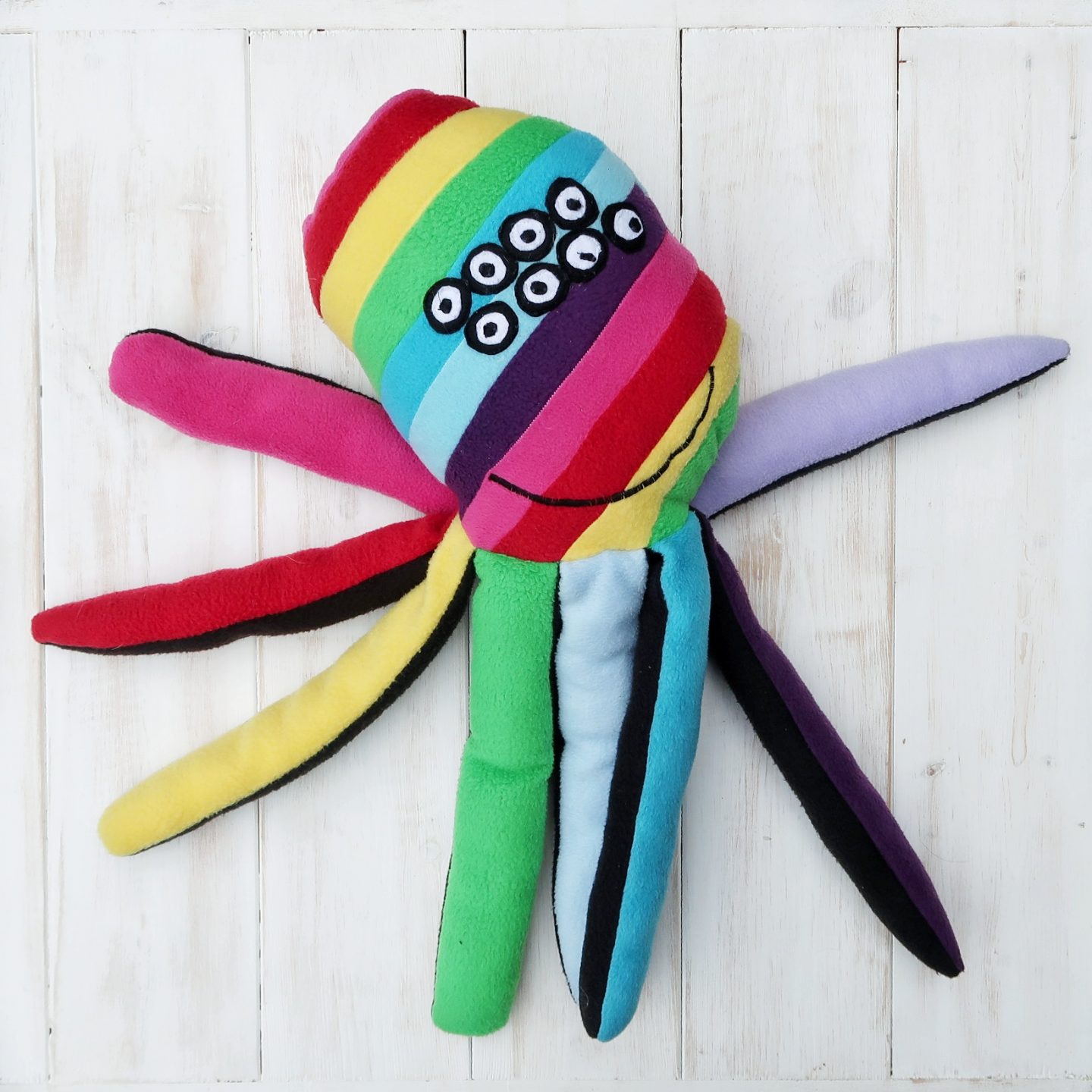 A stuffed spider toy with rainbow colouring