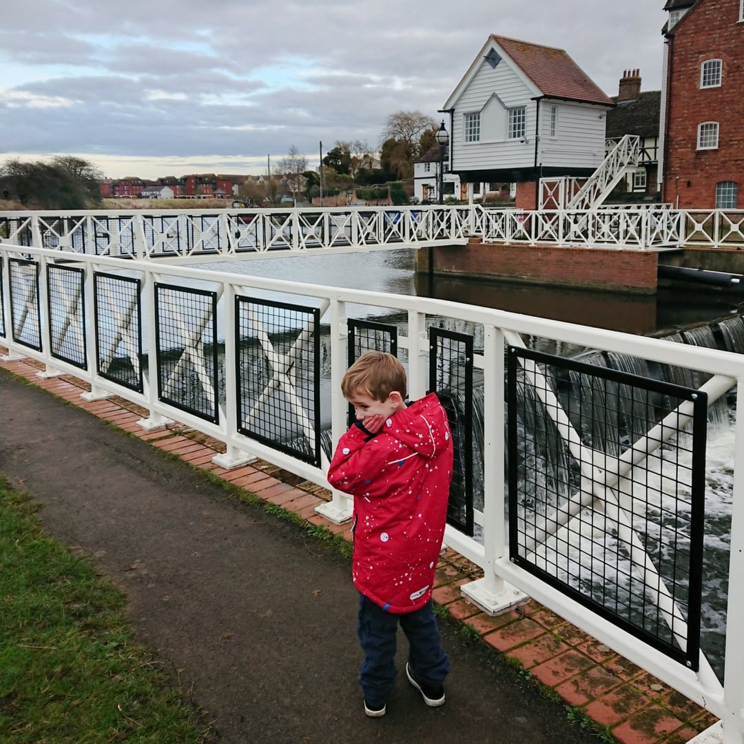 A little boy stands by a river