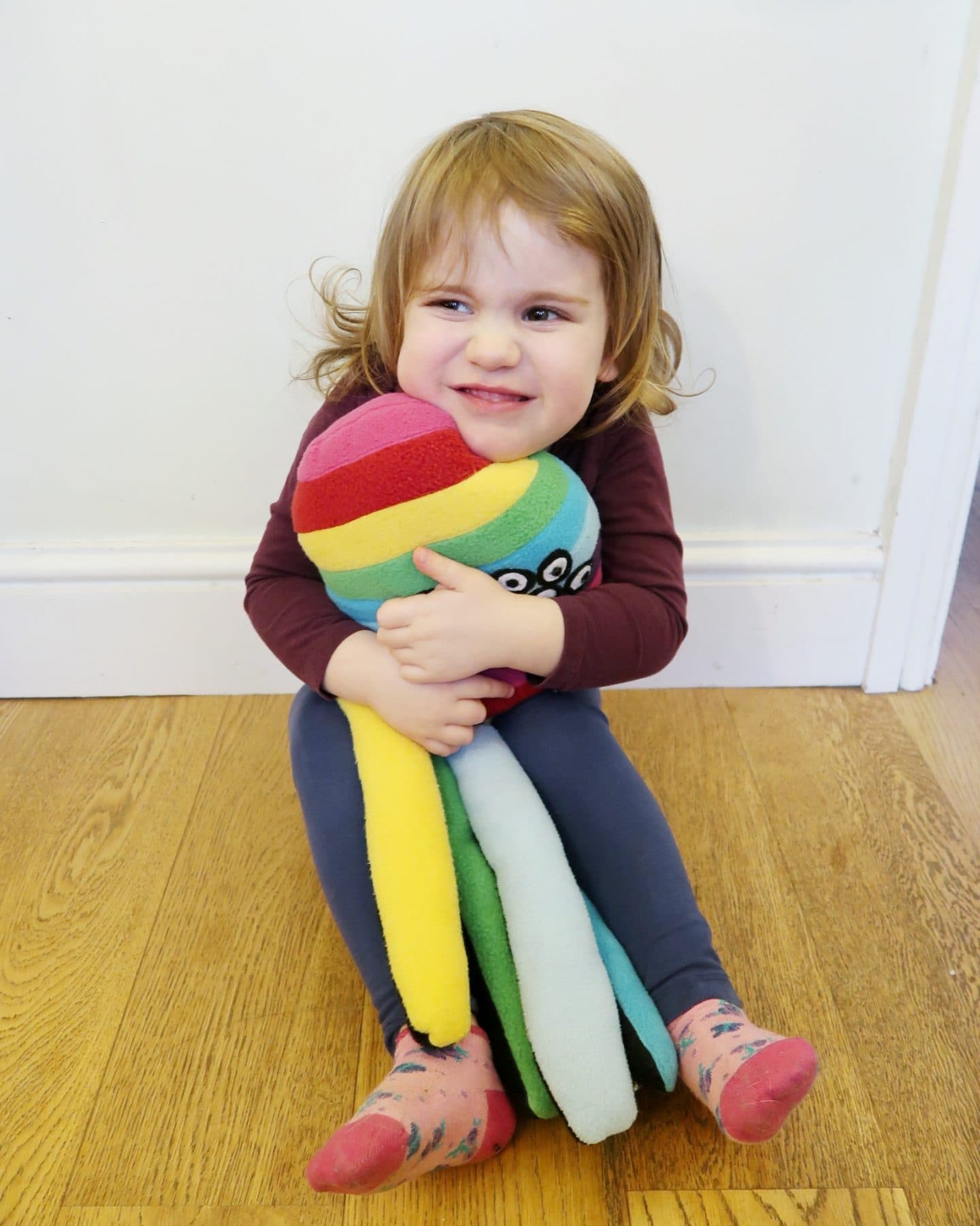 A girl hugging a rainbow spider soft toy