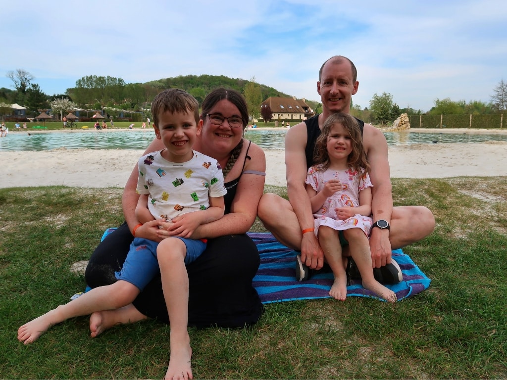 Family of mother, father, boy and girl sitting on the beach.