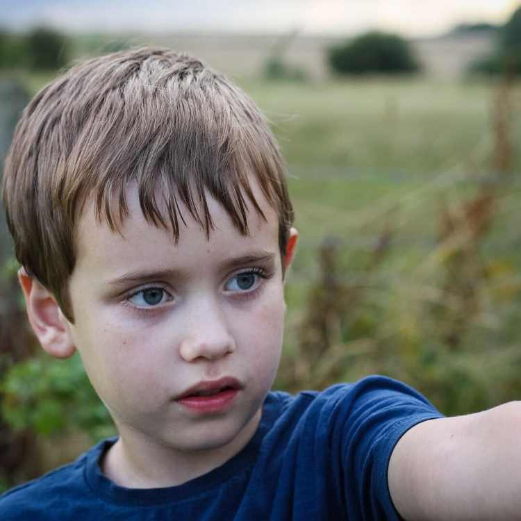 A boy with a field in summer behind him for autism or spoiled