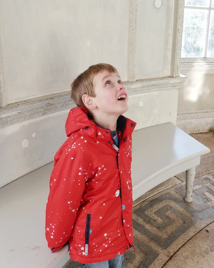 Small boy looking up at ceiling and smiling in the Rotunda at Croome - assumptions about autism