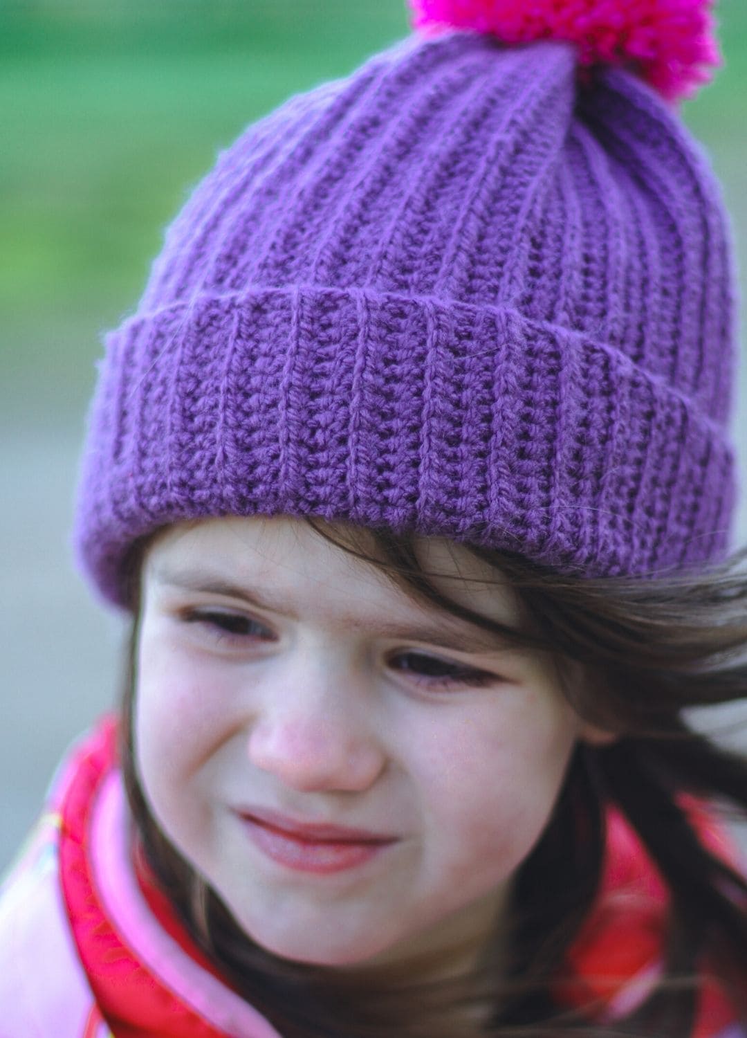 Close-up of small girl in purple bobble-hat